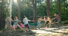 Full Length View Of The Kids At Summer Camp Playing Tug Or War With Their Senior Teacher At The Forest. Happy Childhood And Activities Concept