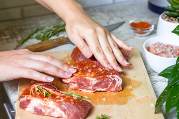 Wall Mural - Raw marbled beef steak slices with salt and spices on wooden cutting board background. The preparation of a fresh meat for dinner.