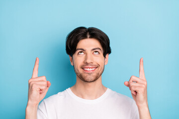 Sticker - Photo of funny young brunet guy point look up empty space wear white t-shirt isolated on blue color background