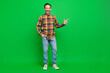 Full length body size view of attractive cheery bearded man showing copy space isolated over bright green color background