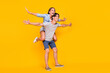 © deagreez - Full length body size view of attractive cheerful carefree couple piggy backing flight jet isolated vivid yellow color background
