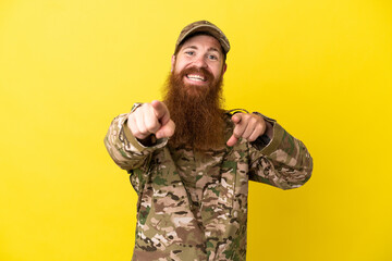 Wall Mural - Military Redhead man over isolated on yellow background points finger at you while smiling