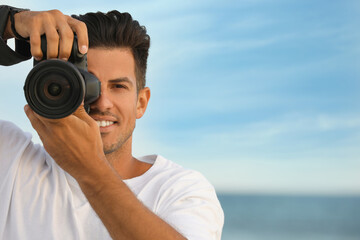 Wall Mural - Photographer taking picture with professional camera near sea