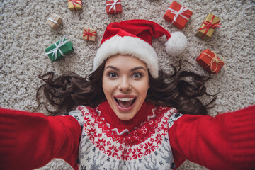 Sticker - Top view photo portrait smiling amazed woman wearing headwear laying on floor in xmas clothes taking selfie