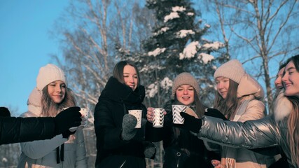 A group of girls are drinking hot tea in winter.