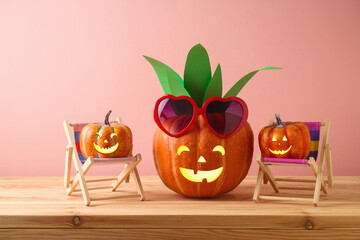 Wall Mural - Halloween pumpkin creative decor as pineapple with sunglasses on wooden table. Handmade decoration for Halloween party concept