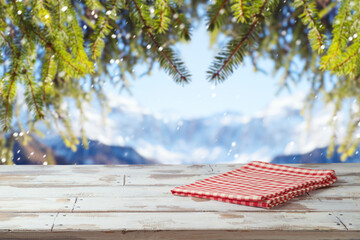 Wall Mural - Empty wooden table with red checked tablecloth over winter landscape background.  Christmas and New Year mock up for design and product display.