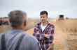 © Budimir Jevtic - Two male farmers standing in harvested soy field talking.