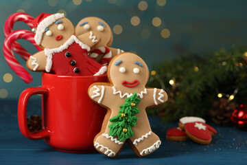 Wall Mural - Delicious homemade Christmas cookies with cup on blue wooden table against blurred festive lights