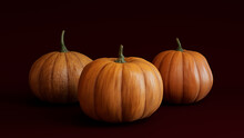 Three Pumpkins On A Deep Plum Red Colored Background. Fall Themed Image.