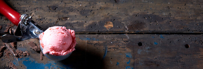 Canvas Print - Scoop of pink strawberry ice cream on a wooden table with a copy spac