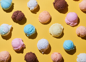 Sticker - Top view of an assortment of ice cream balls and scoops on a yellow table