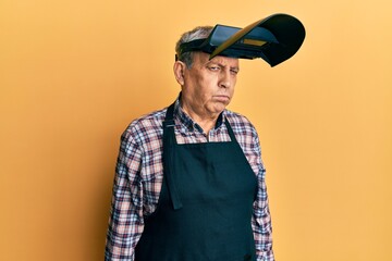 Sticker - Handsome senior man with grey hair wearing welding protection mask skeptic and nervous, frowning upset because of problem. negative person.