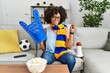 African american woman with afro hair wearing team scarf cheering game holding megaphone smiling happy pointing with hand and finger to the side