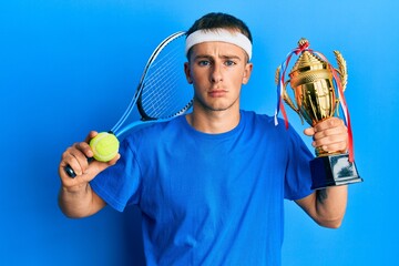 Poster - Young caucasian man playing tennis holding trophy depressed and worry for distress, crying angry and afraid. sad expression.