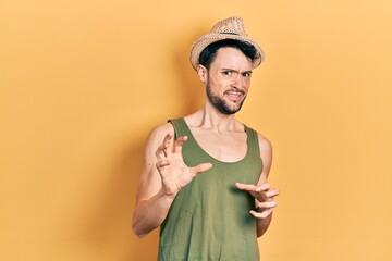 Poster - Young hispanic man wearing summer hat disgusted expression, displeased and fearful doing disgust face because aversion reaction. with hands raised