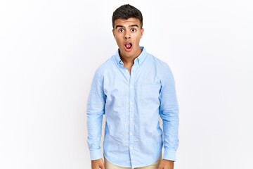 Poster - Young hispanic man wearing business shirt standing over isolated background afraid and shocked with surprise and amazed expression, fear and excited face.