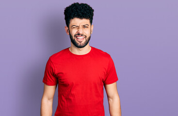 Sticker - Young arab man with beard wearing casual red t shirt winking looking at the camera with sexy expression, cheerful and happy face.