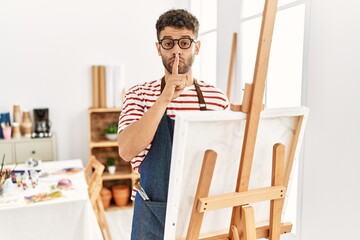 Poster - Arab young man at art studio asking to be quiet with finger on lips. silence and secret concept.