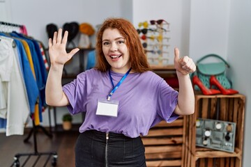 Sticker - Young redhead woman working as manager at retail boutique showing and pointing up with fingers number six while smiling confident and happy.