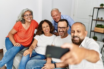 Canvas Print - Group of middle age friends smiling happy make selfie by the smartphone at home.