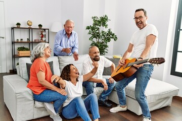 Poster - Group of middle age friends having party playing classical guitar sitting on the sofa at home.