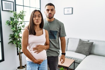 Sticker - Young interracial couple expecting a baby, touching pregnant belly looking at the camera blowing a kiss on air being lovely and sexy. love expression.