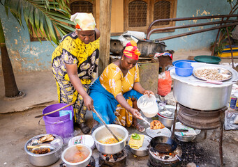 african woman cooking traditional food at street