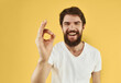 © SHOTPRIME STUDIO - cheerful bearded man in a white t-shirt gesturing with his hands yellow background