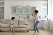© fizkes - Happy two generations family dancing barefoot to energetic music, entertaining at home. Joyful cute little kid boy having fun with caring young indian mother, celebrating freedom.