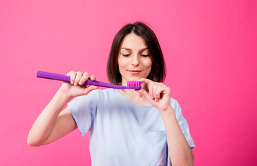 Wall Mural - Beautiful happy young woman with big toothbrush on blank pink background