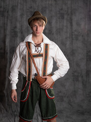 A young man in a national Bavarian suit with shorts on suspenders and a hat.