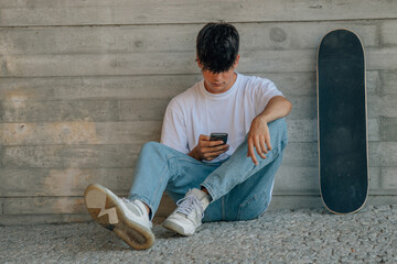 Poster - teenage boy with mobile phone and skateboard on the wall