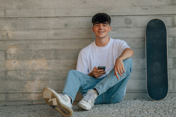 Poster - teenage boy with mobile phone and skateboard on the wall