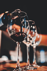 waiter pouring red wine into a glass in cafe or bar