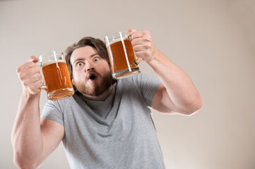 Portrait of a happy young bearded man holding two beer mugs isolated over light gray background