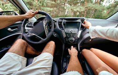 Wall Mural - Young couple in a new car. A man driving a car with his girlfriend and having fun. Buying and renting a car. Travel, tourism, recreation.