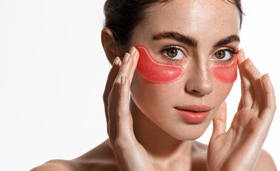 beautiful female model with radiant look, applying pink under eye patches for dark-circles and puffi