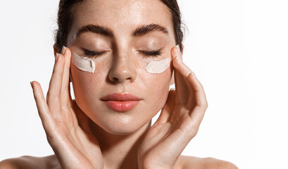 close up beauty girl with freckles and thick eyebrows, applying moisturizing skincare cream, lotion 