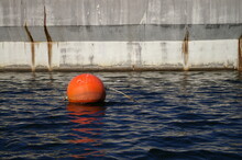 Orange Buoy In Front Of Dam