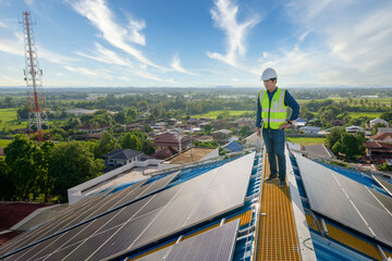 Wall Mural - Asian technician working on a solar power plant using a laptop computer to check the maintenance of solar panels on the roof.