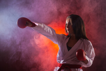 Wall Mural - girl exercising karate punch against red fog background.