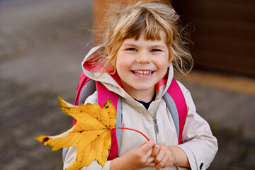 Cute little toddler girl on her first day going to playschool. Healthy happy child walking to nursery school. Kid with backpack going to day care on the city street, outdoors