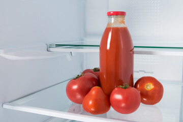 tomato juice in a bottle and tomatoes on a shelf in the refrigerator