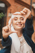 © satura_ - Portrait of young muslim girl making a camera frame with fingers outdoors.