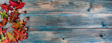 Side Border Of Acorns And Foliage Leaves On Blue Weathered Wooden Planks For The Autumn Holiday Season Of Halloween Or Thanksgiving Background