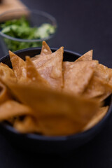 Bowls of tortilla chips and chopped lettuce with black background