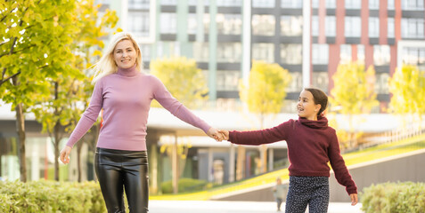 Wall Mural - Little girl and her mother enjoy sunny weather in the autumn park