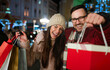 © NDABCREATIVITY - Cheerful happy couple doing Christmas shopping standing on decorated street. Sale people concept