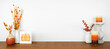 © Jenifoto - Autumn decor on a wood shelf against a white wall banner background. Pumpkin sign, candles and vases with fall colors. Copy space.